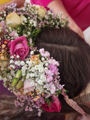 Eine schwangere Person wird mit Blumen umrahmt.